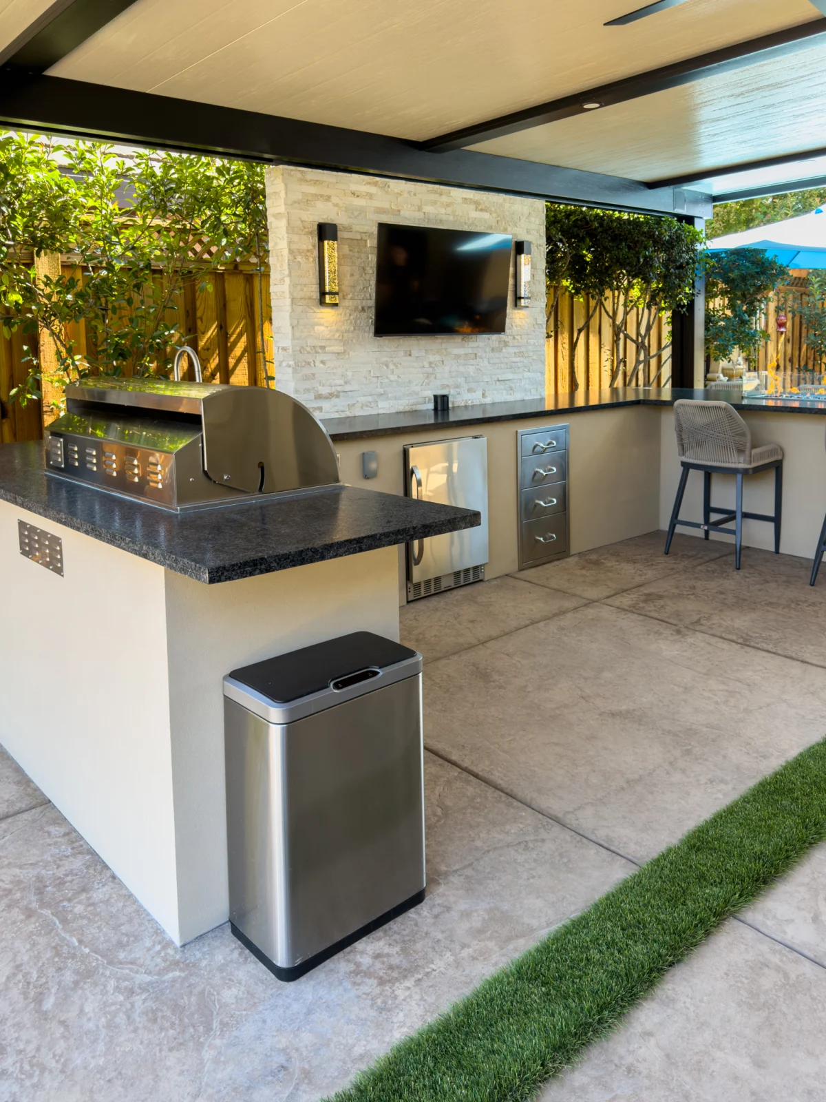 Outdoor kitchen with a grill and a TV under a patio cover