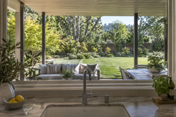 View from a kitchen sink across a covered patio to the lawn