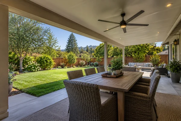 Shaded dining area under a patio cover beside a sunny lawn