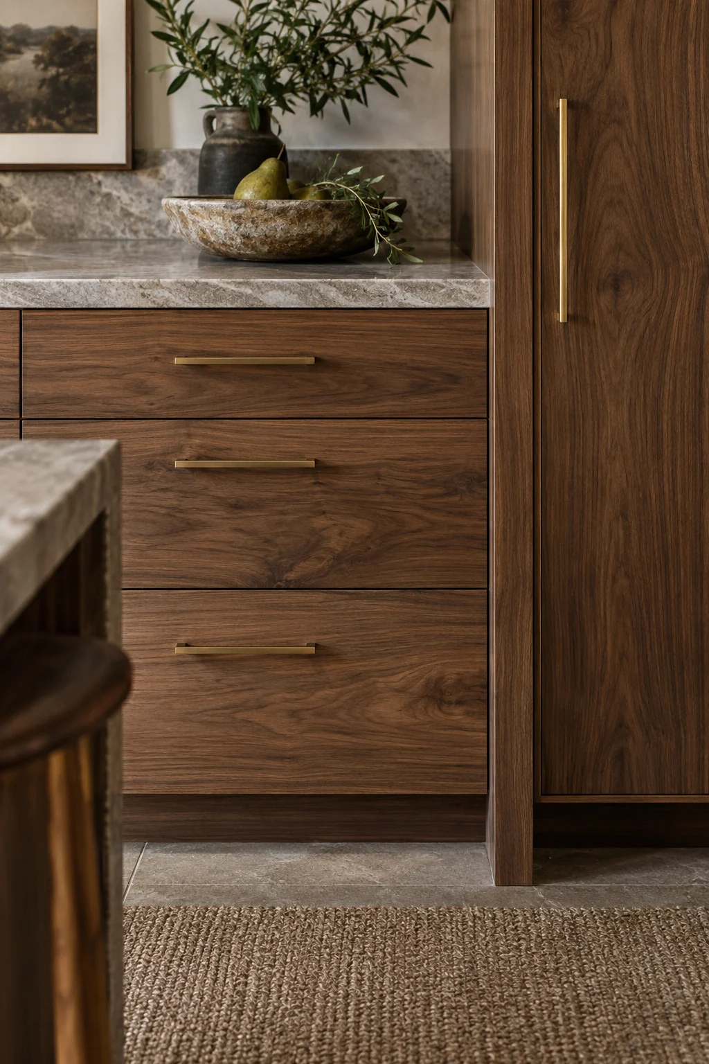 Walnut drawers and a tall pantry cabinet beside a stone counter