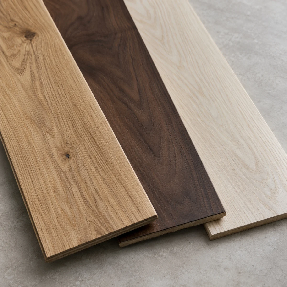 Three wood flooring planks in light oak, walnut and white oak