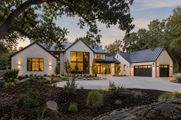 White two-story house with a curved driveway at dusk