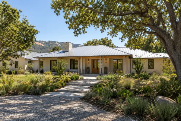 Single-story house with a pale metal roof under shade trees