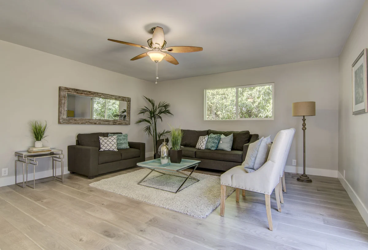 Living room with gray sofas, a ceiling fan and light floors