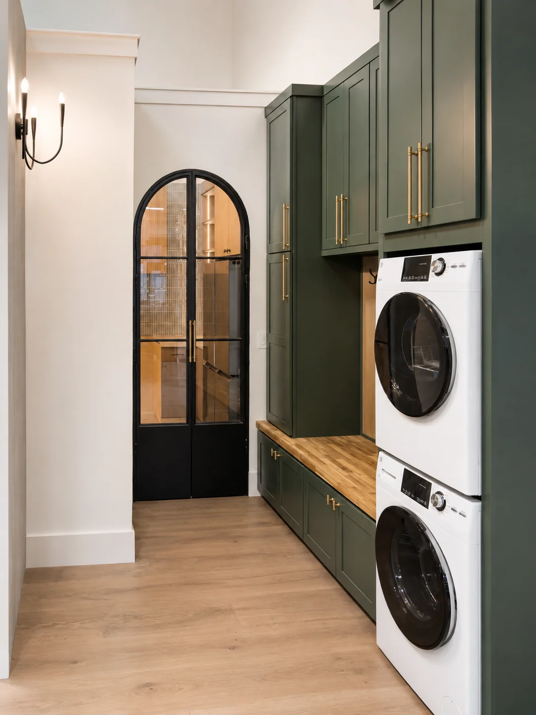 Laundry nook with stacked washer and dryer and green cabinets