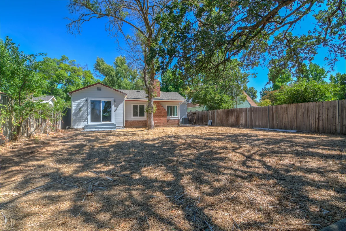 Small house at the back of a large lot with mature trees