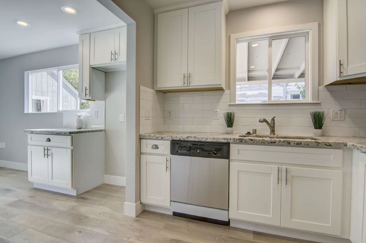 White kitchen with granite counters and a dishwasher