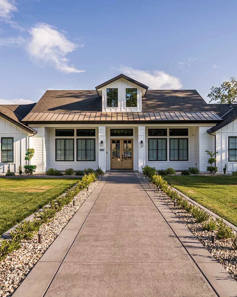 White farmhouse with a long front walkway and lawn