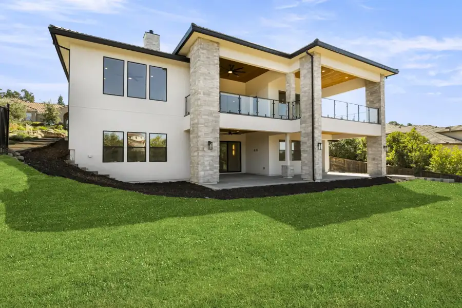 Rear of a two-storey Solid custom home showing its covered patio and the covered terrace above it