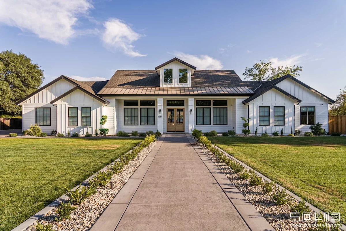 White farmhouse with a long front walkway and lawn