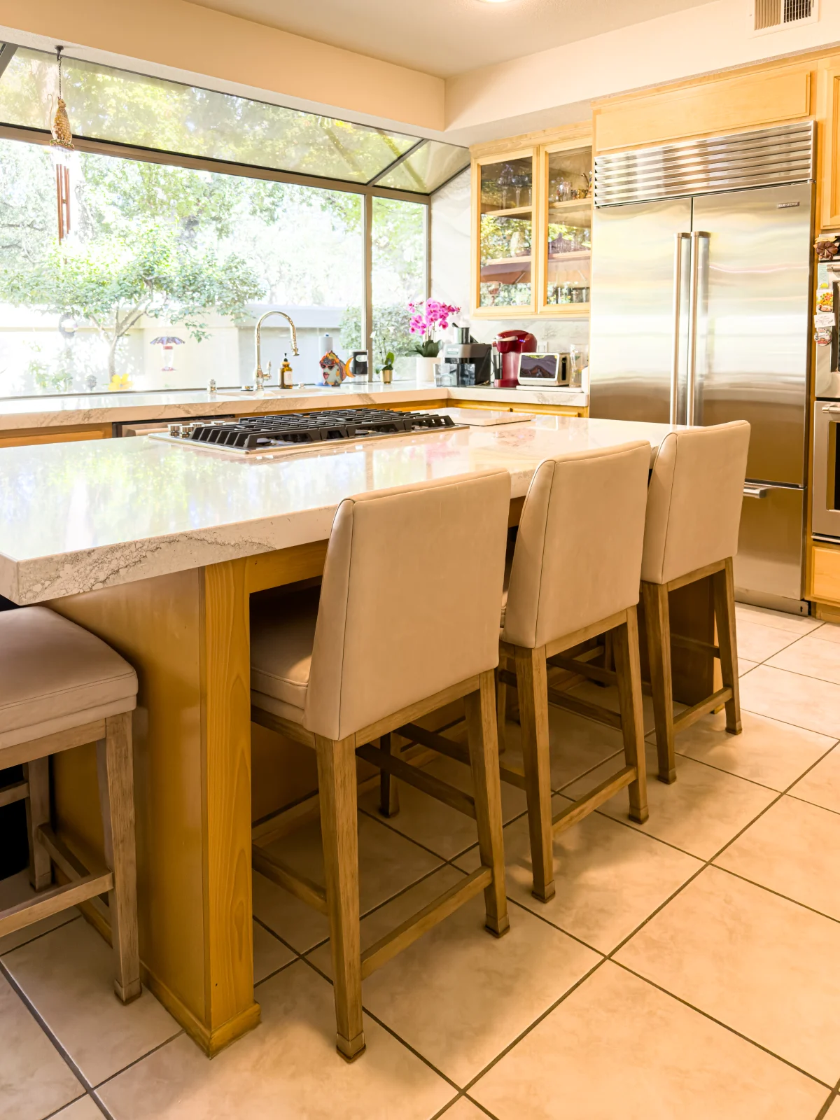 Kitchen with a wood island, counter stools and a large window