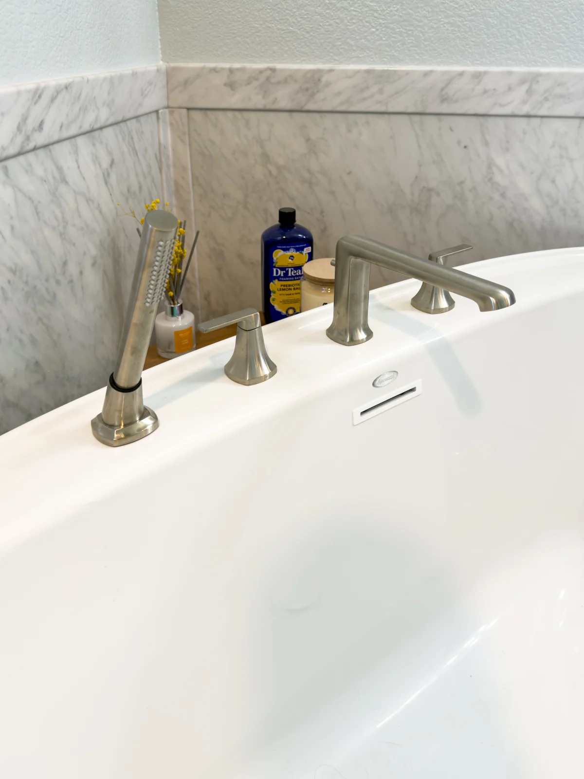 Tub filler on the edge of a white soaking tub