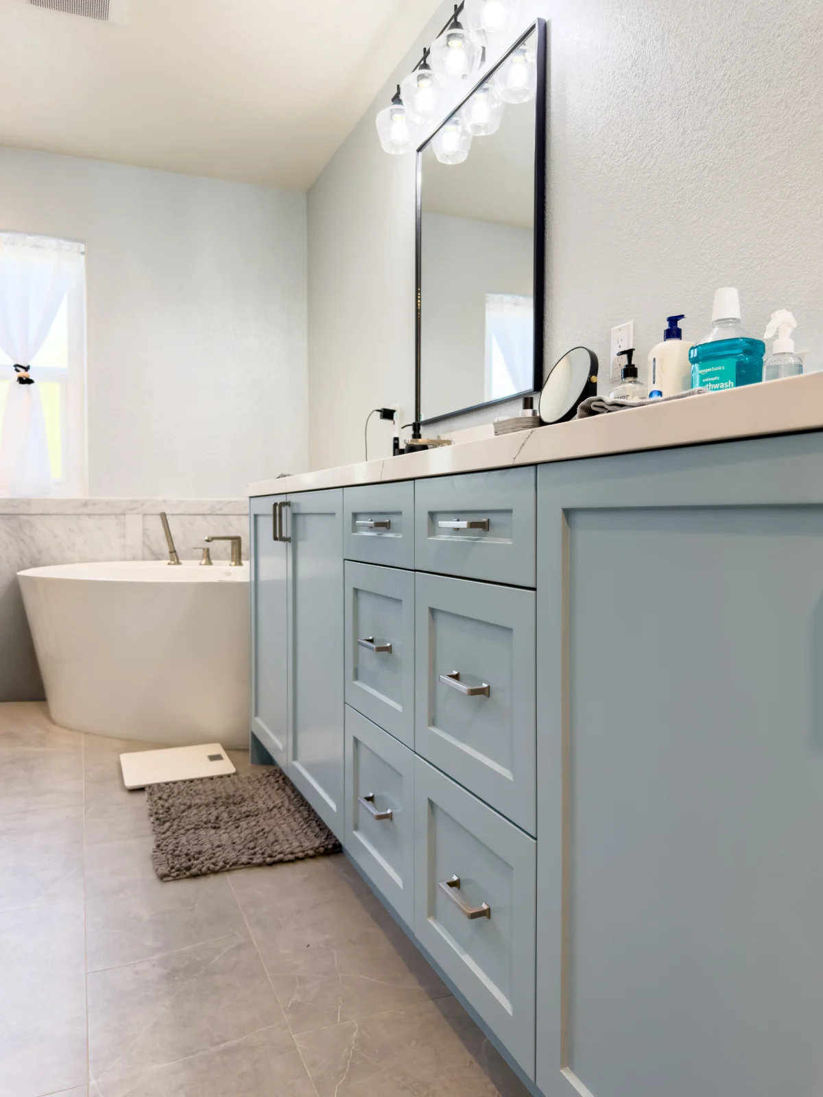 Bathroom with a light blue vanity and a freestanding tub